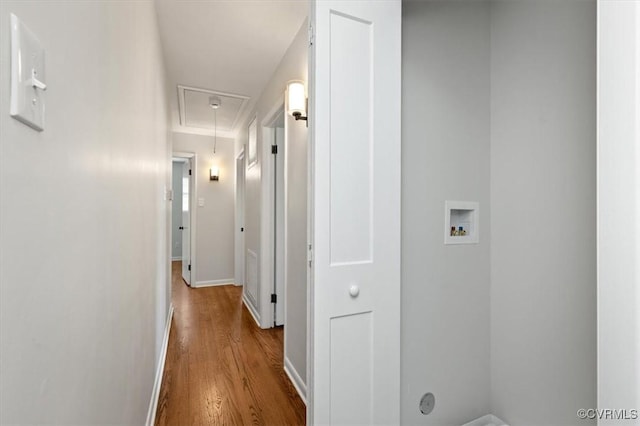 hallway with baseboards, attic access, and wood finished floors
