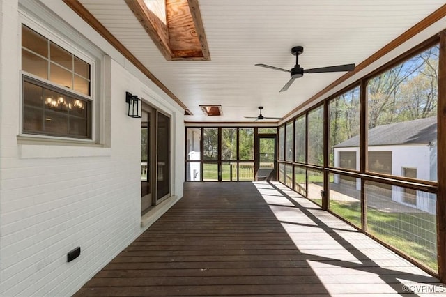 unfurnished sunroom featuring a ceiling fan and a skylight