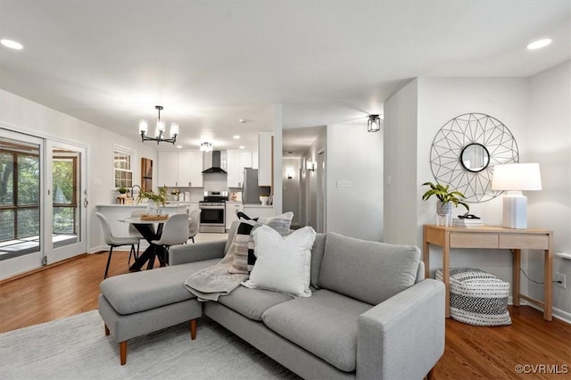 living area with light wood-style flooring, recessed lighting, an inviting chandelier, and baseboards