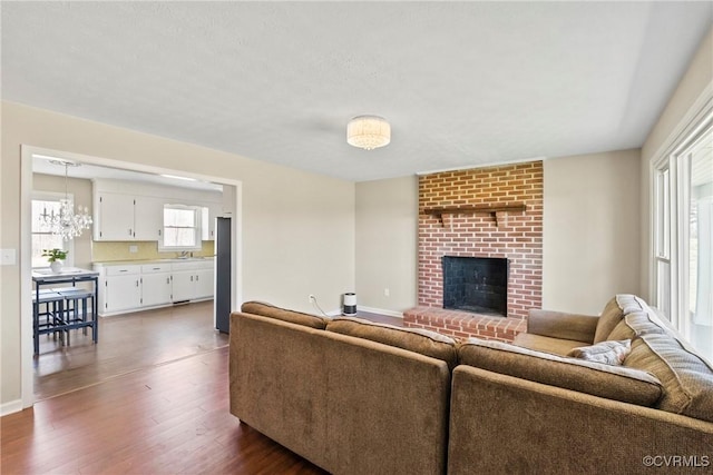 2407 Crawley Rd, Cullen, VA 23924 - living area with baseboards, an inviting chandelier, a brick fireplace, and dark wood finished floors