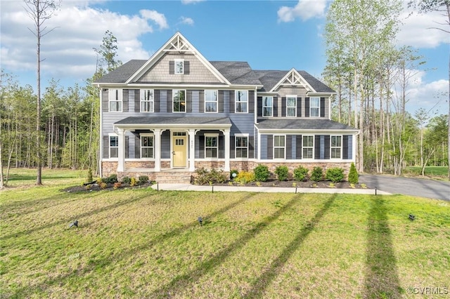 view of front of home with stone siding, a front lawn, and covered porch