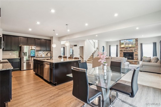 dining room featuring light wood-type flooring, a fireplace, recessed lighting, and stairs
