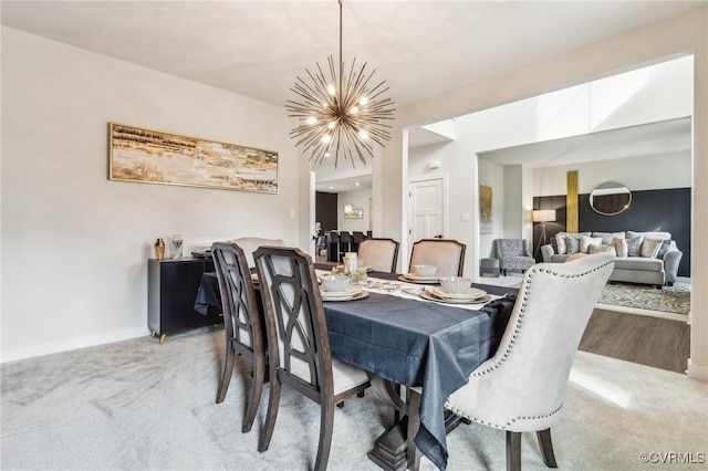 dining area featuring light colored carpet, baseboards, and a chandelier