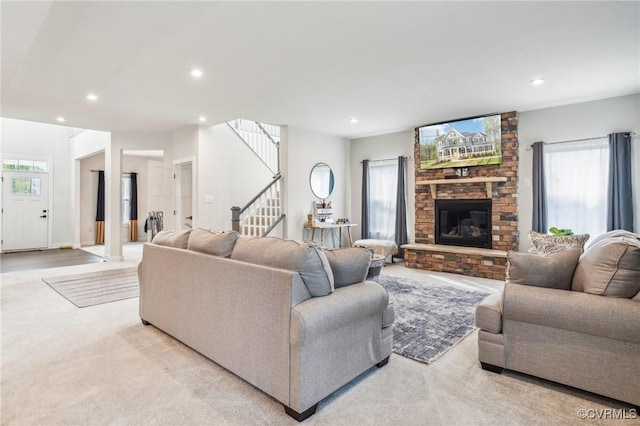 living room with recessed lighting, a stone fireplace, stairs, and light colored carpet