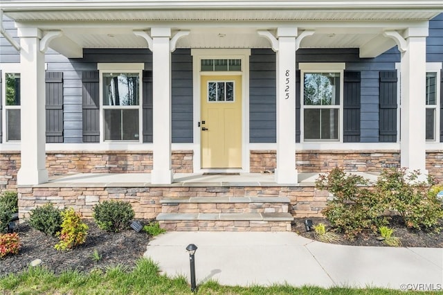 view of exterior entry featuring stone siding and a porch