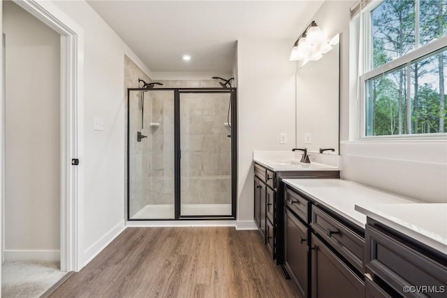 full bath featuring a shower stall, baseboards, vanity, and wood finished floors