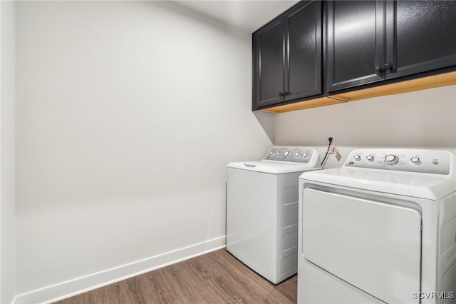 laundry area featuring cabinet space, wood finished floors, baseboards, and separate washer and dryer