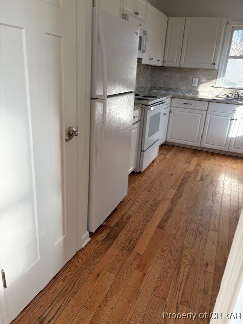 kitchen featuring white appliances, white cabinetry, tasteful backsplash, and light wood-style floors