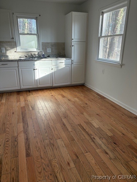 kitchen featuring decorative backsplash, white cabinets, a sink, and light wood finished floors