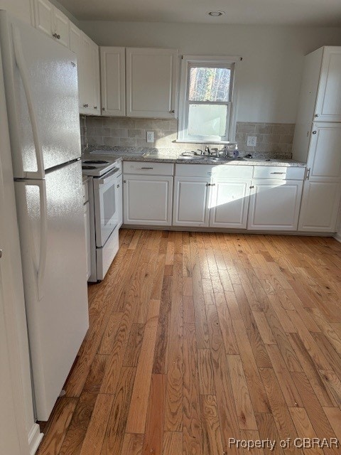 kitchen featuring white appliances, white cabinetry, light wood-style flooring, and decorative backsplash