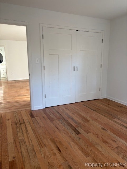 unfurnished bedroom featuring baseboards, a closet, and wood-type flooring