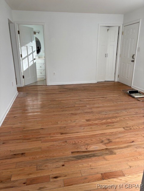 spare room featuring baseboards and light wood-type flooring