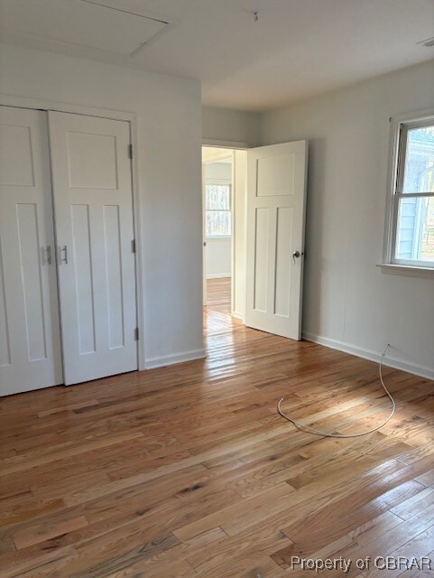 unfurnished bedroom featuring light wood-style flooring, a closet, and baseboards