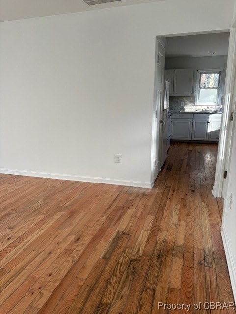 unfurnished dining area featuring dark wood finished floors and baseboards