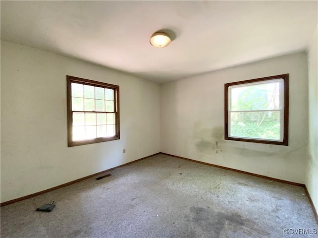 empty room featuring baseboards, visible vents, and carpet flooring