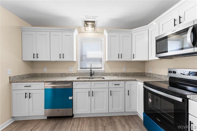 1713 Boydton Plank Rd, Petersburg, VA 23805 - kitchen with a sink, white cabinets, light wood-style floors, and appliances with stainless steel finishes