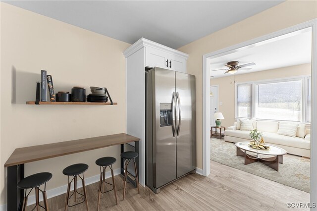 1713 Boydton Plank Rd, Petersburg, VA 23805 - kitchen with a ceiling fan, stainless steel fridge with ice dispenser, white cabinetry, a kitchen breakfast bar, and light wood-style floors