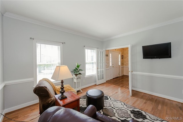 living area featuring baseboards, ornamental molding, and light wood finished floors