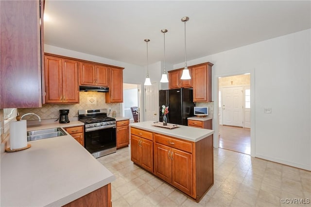 kitchen with under cabinet range hood, light floors, a sink, freestanding refrigerator, and stainless steel range with gas cooktop
