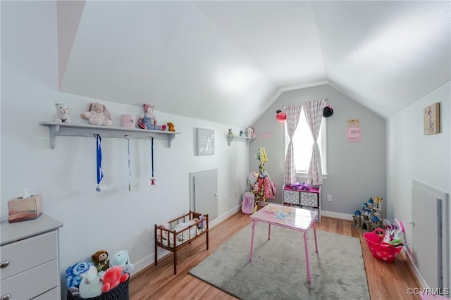 recreation room with vaulted ceiling, wood finished floors, and baseboards