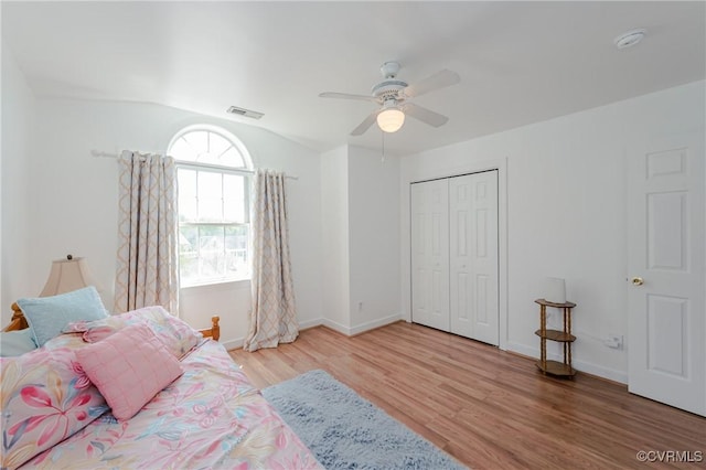bedroom with lofted ceiling, wood finished floors, visible vents, a closet, and baseboards