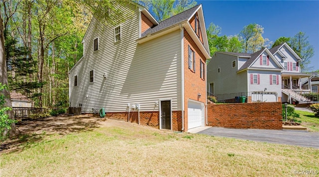 exterior space with a garage, cooling unit, a lawn, and aphalt driveway