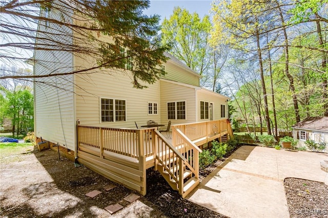 back of house with a wooden deck and a patio