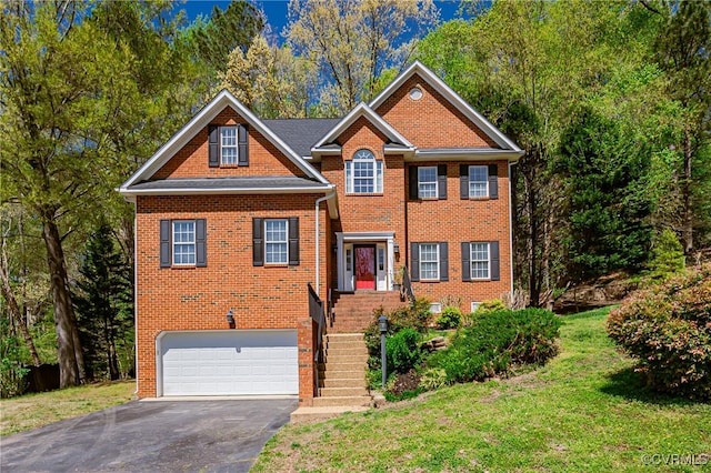 traditional-style house with a front lawn, aphalt driveway, brick siding, and a garage