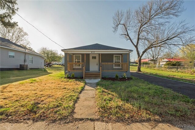 bungalow with a porch, fence, and a front lawn