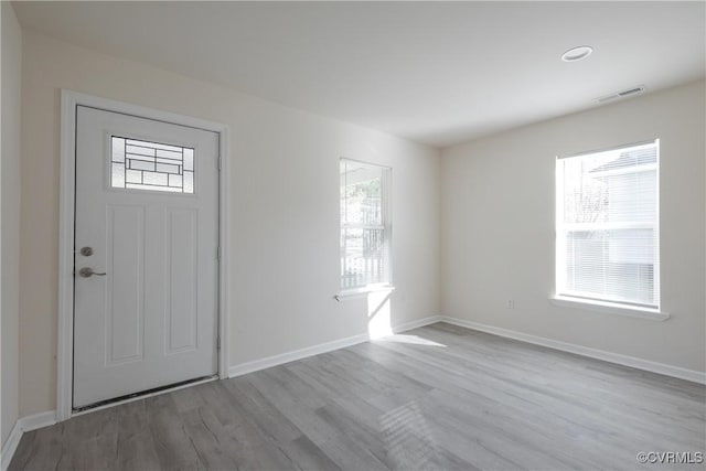 foyer featuring baseboards, visible vents, and wood finished floors