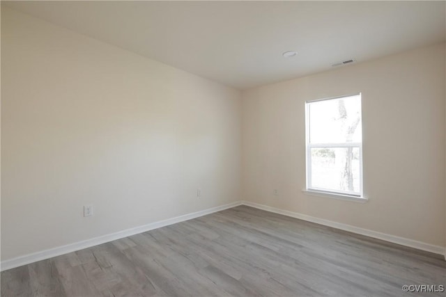 spare room with visible vents, baseboards, and wood finished floors