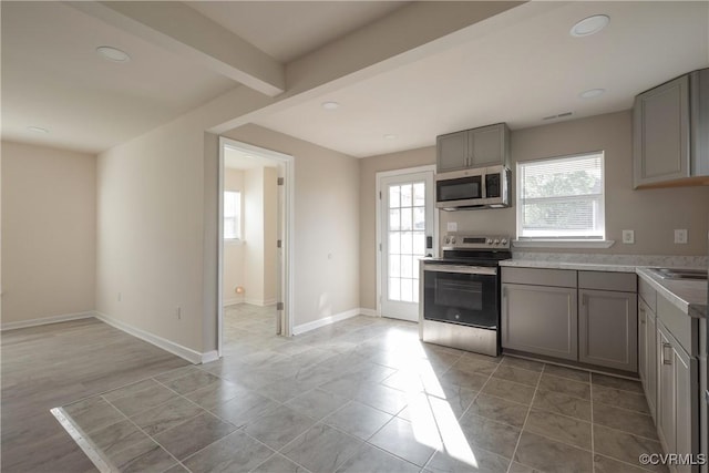 kitchen with light countertops, gray cabinets, stainless steel appliances, and beam ceiling