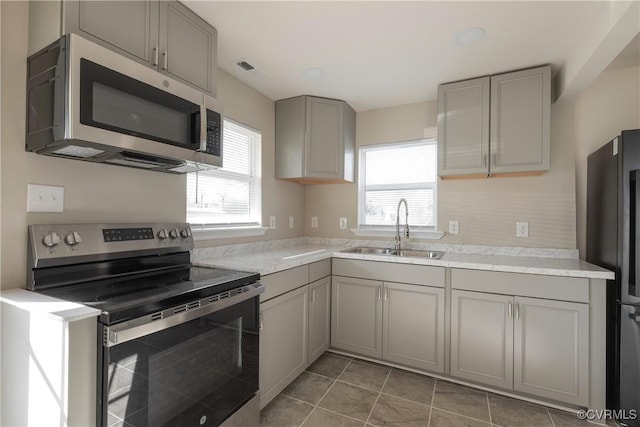 kitchen featuring gray cabinetry, a wealth of natural light, a sink, and appliances with stainless steel finishes
