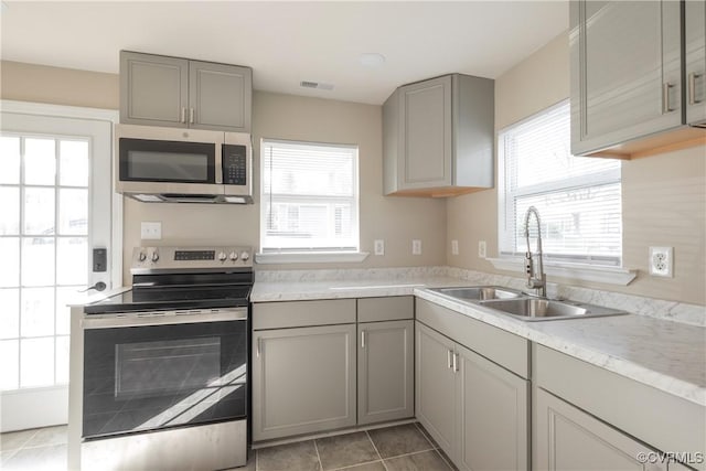 kitchen featuring gray cabinetry, light countertops, a sink, and stainless steel appliances