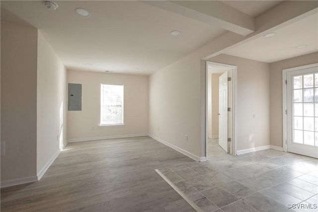 empty room featuring light wood-style flooring, baseboards, and electric panel
