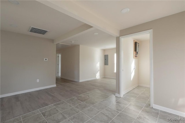 spare room featuring electric panel, baseboards, visible vents, and light wood-type flooring