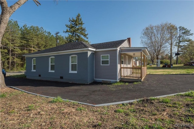 view of home's exterior with crawl space, a shingled roof, and covered porch