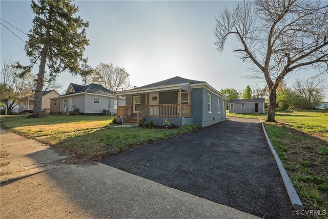 view of front of house featuring driveway, a porch, and a front yard