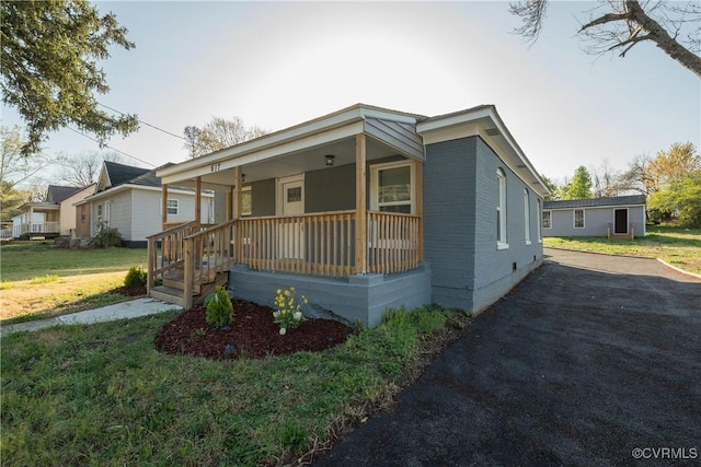 view of front facade with crawl space, brick siding, a front lawn, driveway, and a porch