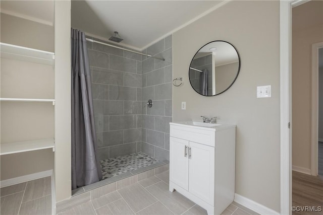 bathroom with vanity, baseboards, and a tile shower