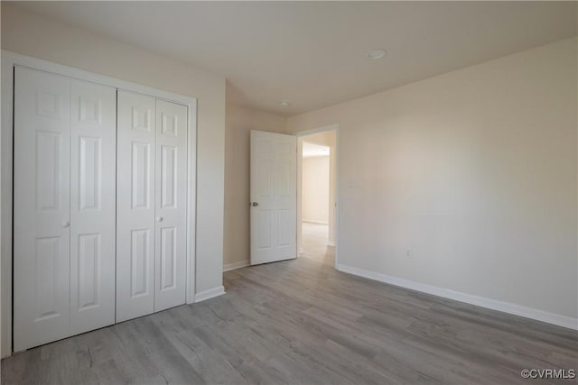 unfurnished bedroom with a closet, baseboards, and wood finished floors