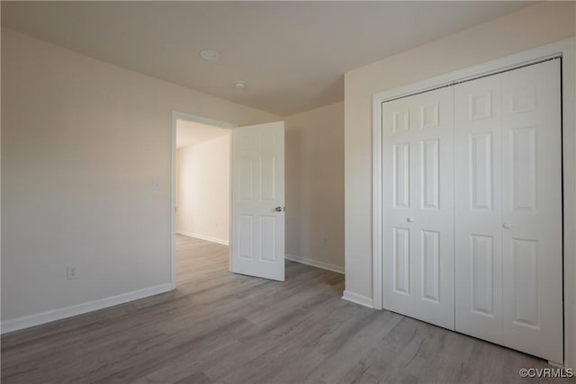 unfurnished bedroom with baseboards, a closet, and wood finished floors