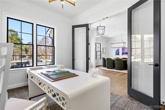 dining space with crown molding, a notable chandelier, wood finished floors, and a healthy amount of sunlight