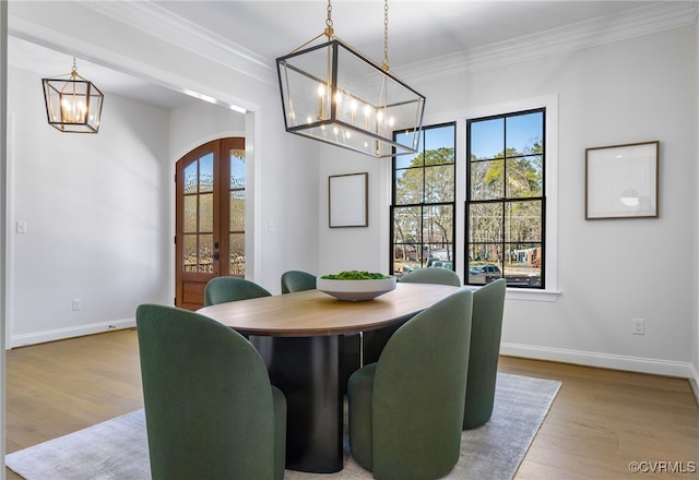 dining room featuring wood finished floors, an inviting chandelier, french doors, and crown molding