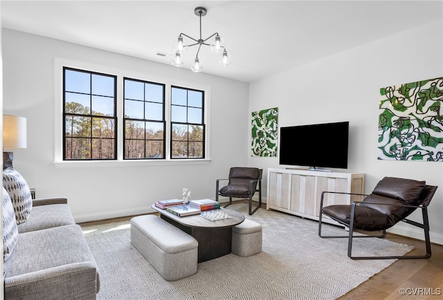 living area with baseboards, wood finished floors, and a notable chandelier
