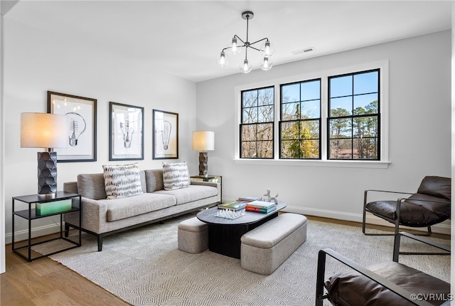 living room featuring a notable chandelier, visible vents, wood finished floors, and baseboards