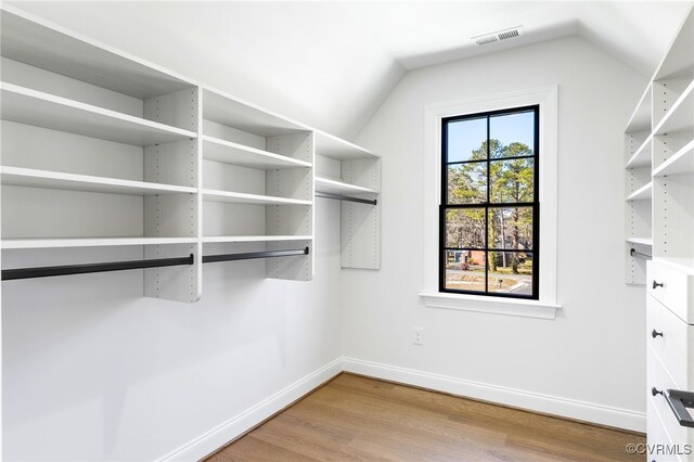 spacious closet featuring lofted ceiling, wood finished floors, and visible vents