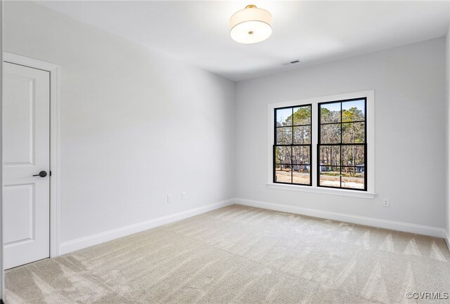 spare room featuring carpet, visible vents, and baseboards