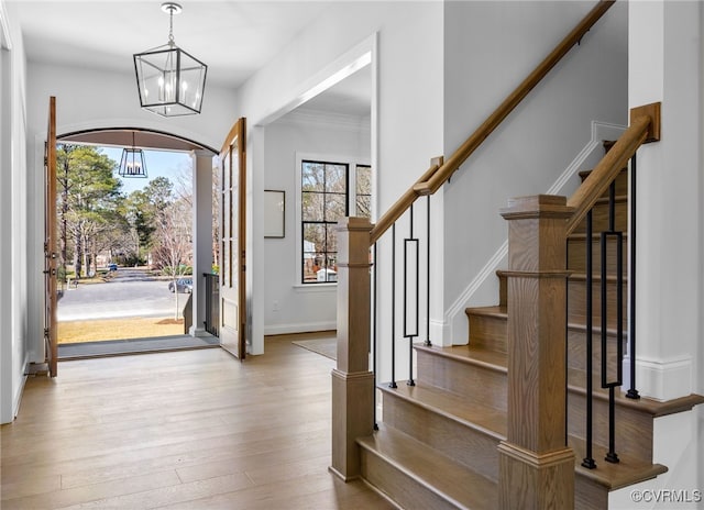 foyer with stairs, an inviting chandelier, wood finished floors, and baseboards