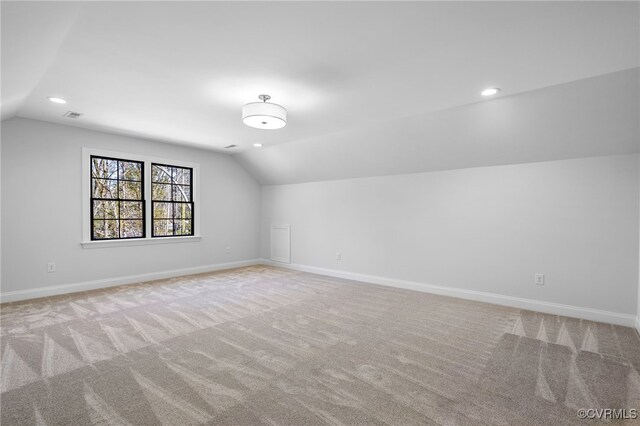 additional living space featuring lofted ceiling, baseboards, and light carpet